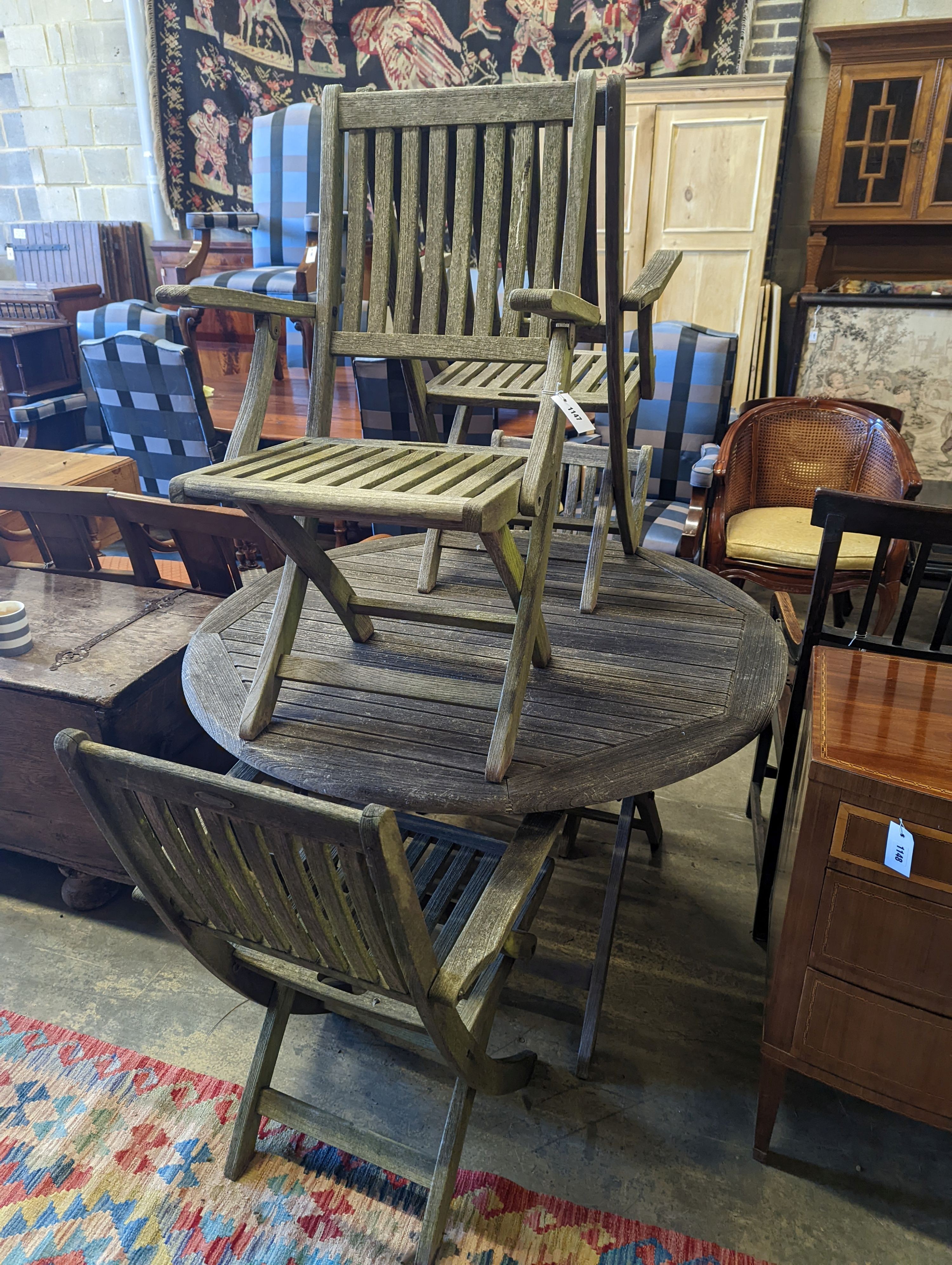 A set of four Westminster teak folding elbow chairs and a weathered teak circular garden table, diameter 120cm, height 73cm